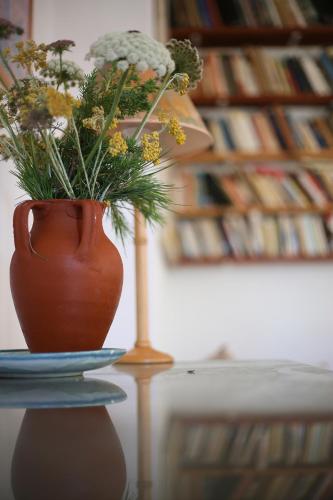 a vase on a table with a blue plate and flowers at Case di Berto in Capo Vaticano