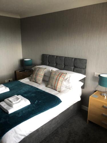 a bedroom with a large bed with white sheets and pillows at Sinclair Bay Apartments in Keiss
