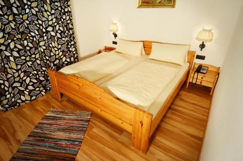Schlafzimmer mit einem Holzbett mit weißer Bettwäsche in der Unterkunft Tutzinger Hof in Tutzing