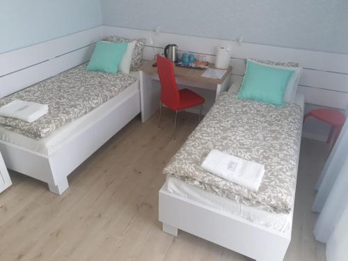 a room with two beds and a table with a red chair at Willa Mazury in Iława