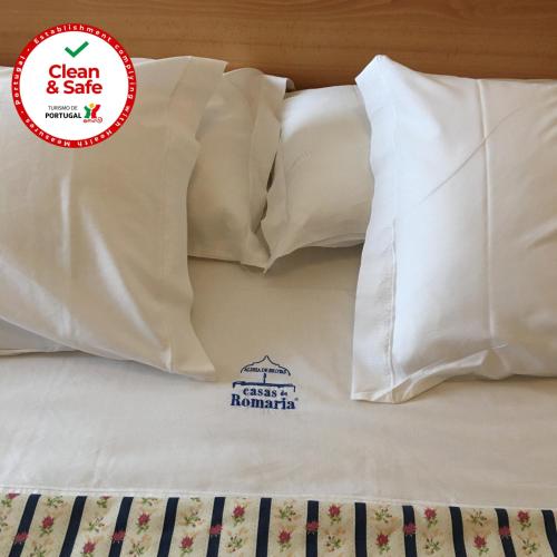 a bed with white pillows with a sticker on it at Casas De Romaria in Brotas