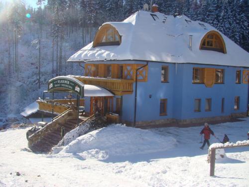 a house in the snow with a person in front of it at Hotel Vladimír in Janske Lazne