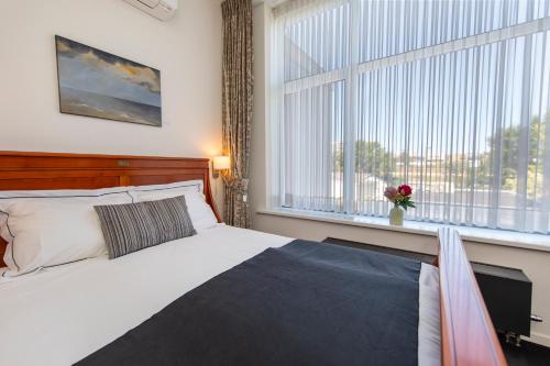 a bedroom with a bed and a large window at Hotel La Rosa Amsterdam Beach in Zandvoort