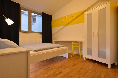 a bedroom with a bed and a desk with a yellow chair at Townside Hostel Bremen in Bremen