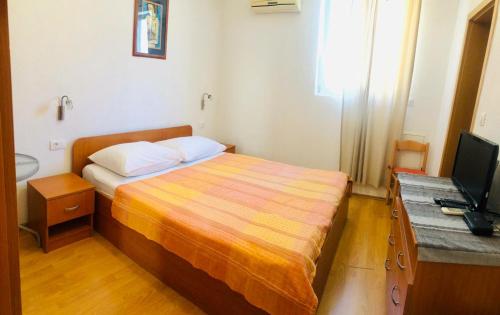 a small bedroom with a bed and a television at Apartman Lala in Baška Voda