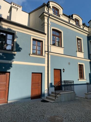 a large white building with brown doors and stairs at Apartament w sercu Zamojskiej Starówki in Zamość