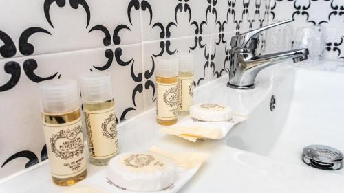 ein weißes Waschbecken mit drei Flaschen Parfüm in der Unterkunft MainStreet, VintageGroup in Espinho