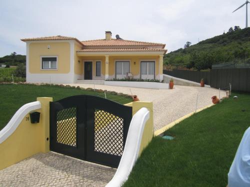 a house with a black gate in front of a yard at Casinha de férias no campo - Quintinha dos Cavalos - Arruda dos Vinhos in Sabugos