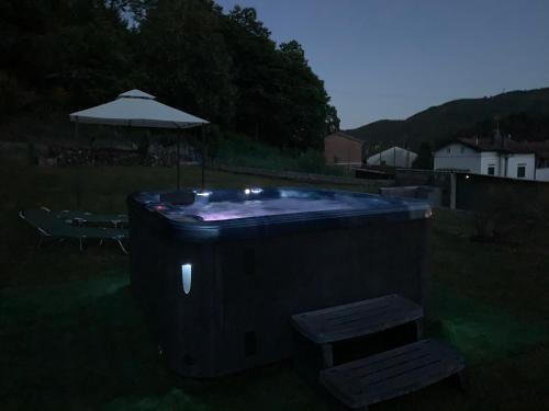 a hot tub in a yard with an umbrella at Nidi del faggio rosso - Family Holiday Home in Maresca
