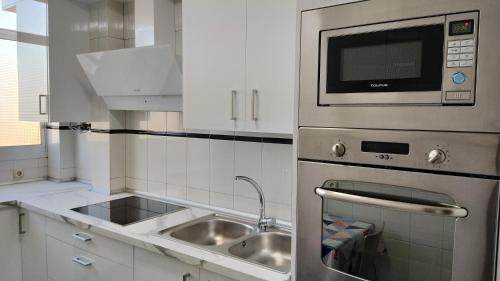 een keuken met een wastafel en een magnetron bij Apartamento San Juan Bosco in Almería