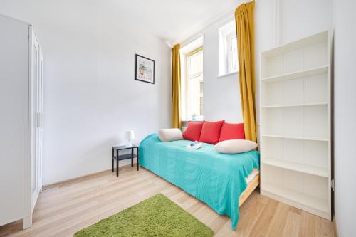 a bedroom with a bed with red pillows and a window at Kurhaus Gdynia Pokoje in Gdynia