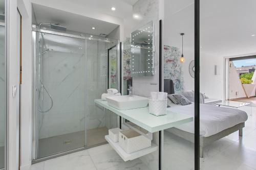 bagno bianco con lavandino e doccia di Village Naturiste - Le Diamond X Héliopolis Luxe a Cap d'Agde