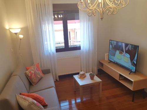 ein Wohnzimmer mit einem Sofa und einem Flachbild-TV in der Unterkunft Apartamento en la playa con parking privado in Getxo