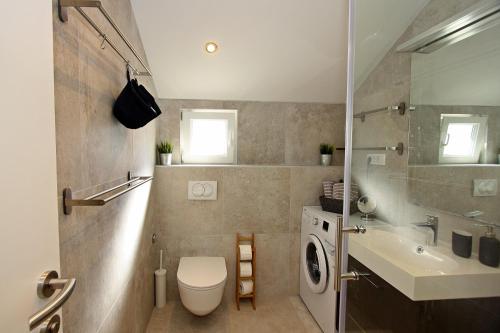 een badkamer met een toilet, een wastafel en een wasmachine bij Apartman Gajka in Supetar