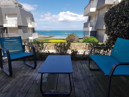 - deux chaises et une table sur une terrasse avec vue sur l'océan dans l'établissement Les pieds dans l'eau, à Saint-Quay-Portrieux