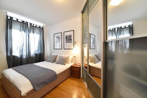 een kleine slaapkamer met een bed en een spiegel bij BLOCK APARTMENT PARK with private garage parking in Zagreb