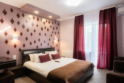 a bedroom with a large bed and red curtains at Rhombus Hotel in Luts'k