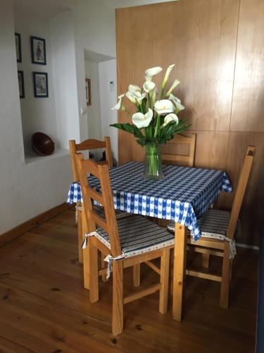 a dining room table with a vase of flowers on it at Casas De Romaria in Brotas