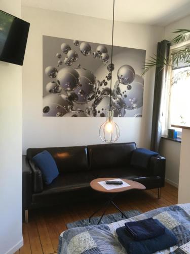 ein Wohnzimmer mit einem schwarzen Sofa und einem Tisch in der Unterkunft Sveriges minsta Hotell! Hôtel Gruyère in Landskrona