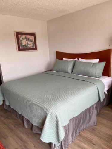 a bedroom with a large bed with a blue comforter at Colonial Inn in Shawnee