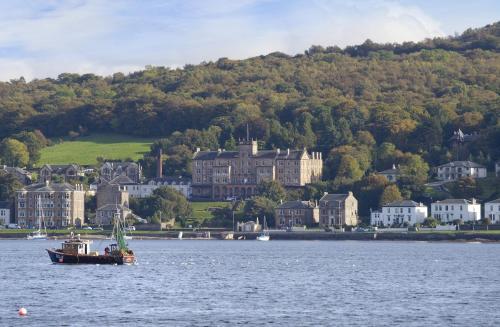 a boat in the water in front of a town at The Glenburn Hotel in Rothesay