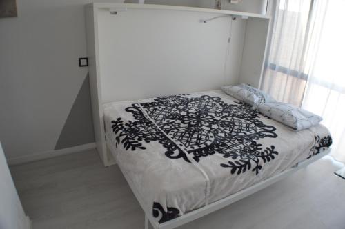 een slaapkamer met een bed met een zwart-witte deken bij Joli studio rénové Emplacement idéal front de mer in Cabanas de Tavira