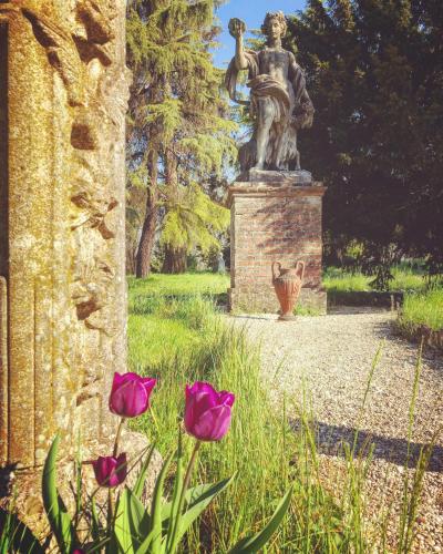 a statue of a woman in a park with pink flowers at Charme of Villa Capannina in Novi Ligure