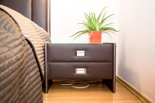 a nightstand with a plant on it next to a bed at Arpad Bridge Apartments in Budapest