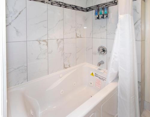 a white bath tub with a shower curtain in a bathroom at Surf Motel and Gardens in Fort Bragg
