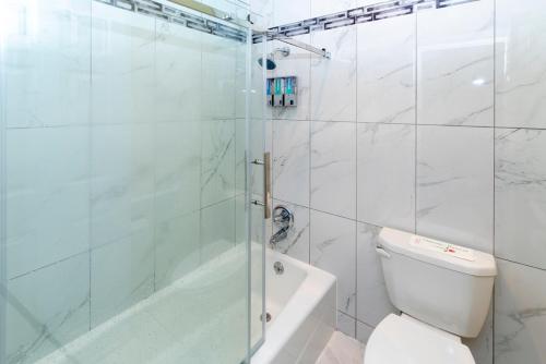 a white bathroom with a shower and a toilet at Surf Motel and Gardens in Fort Bragg