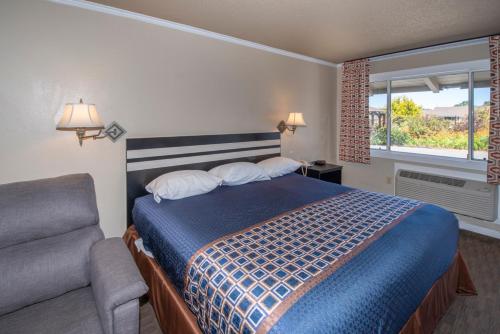 a bedroom with a bed and a couch and a window at Surf Motel and Gardens in Fort Bragg