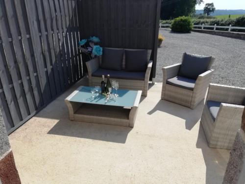eine Terrasse mit 2 Stühlen und einem Tisch in der Unterkunft Le Cottage de L Abbaye in Lonlay-lʼAbbaye