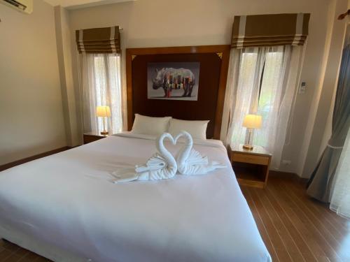 two swans are sitting on top of a bed at Chaithalay Khanom Resort in Ban Phang Phrao
