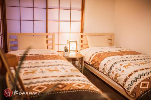 two beds sitting next to each other in a room at KONAYUKI in Myoko