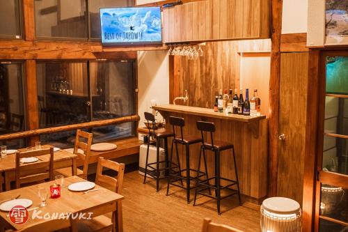 a restaurant with wooden tables and chairs and a bar at KONAYUKI in Myoko