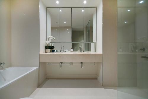 a bathroom with a sink and a tub and a mirror at Platinum Luxury Stays at Freshwater Place in Melbourne
