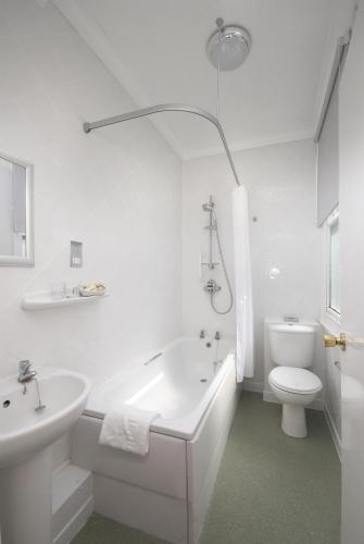 a white bathroom with a tub and a toilet and a sink at The Glenburn Hotel in Rothesay