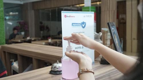a woman is holding a glass of pink drink at RedDoorz near Malioboro Mall 2 in Yogyakarta