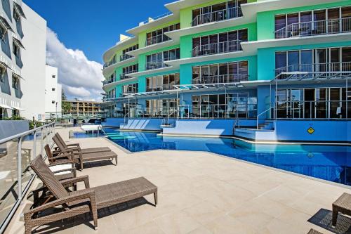 a swimming pool in front of a building at Rolling Surf Resort in Caloundra