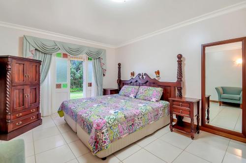 a bedroom with a bed and a dresser and a mirror at Williams Lodge in Yungaburra