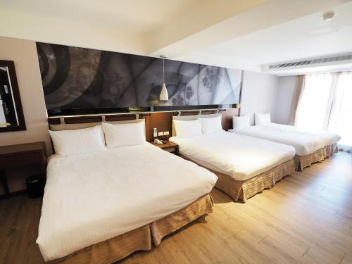 a hotel room with two beds with white sheets at Kailan Hotel in Toucheng