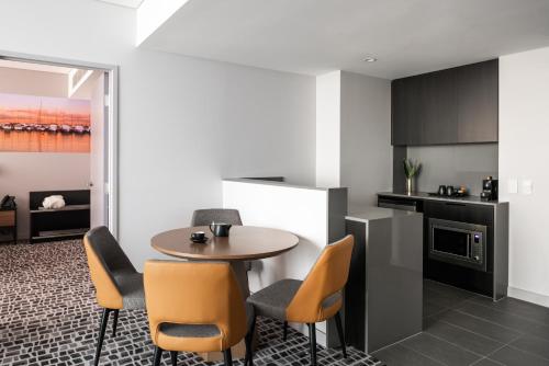 a kitchen and dining room with a table and chairs at Novotel Perth Murray Street in Perth