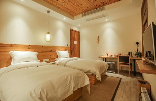 two beds in a room with a desk and a desk at Villa EN Emerald Valley, Huangshan in Huangshan Scenic Area