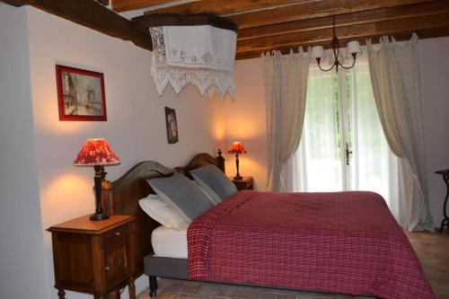 a bedroom with a bed with a red blanket and a window at Maison d'Hôtes La Chouanniere in Brion