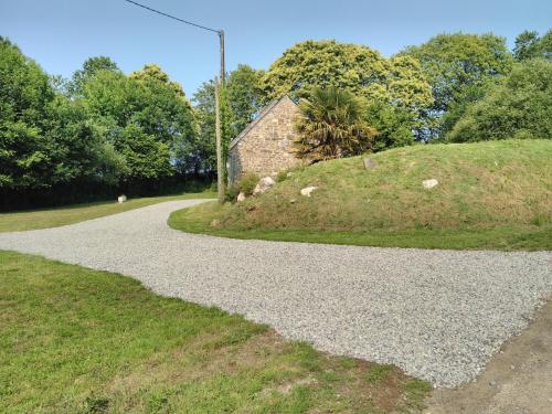 a gravel road next to a grassy hill at Le Botcol in Plouguernével