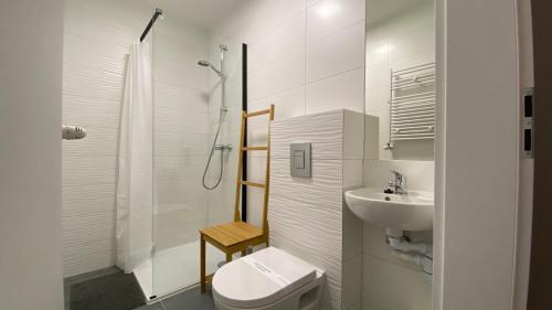 a white bathroom with a toilet and a sink at Sunrise Apartamenty in Łeba
