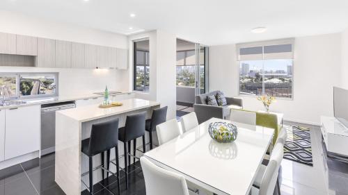 a kitchen and dining room with a white table and chairs at Oaks Brisbane Woolloongabba Suites in Brisbane