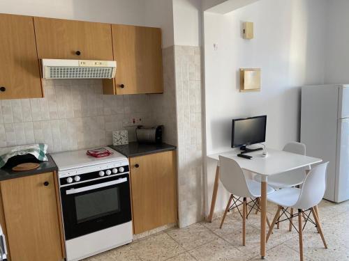 a small kitchen with a table and a computer monitor at Orphanides Latchi Apartment in Polis Chrysochous