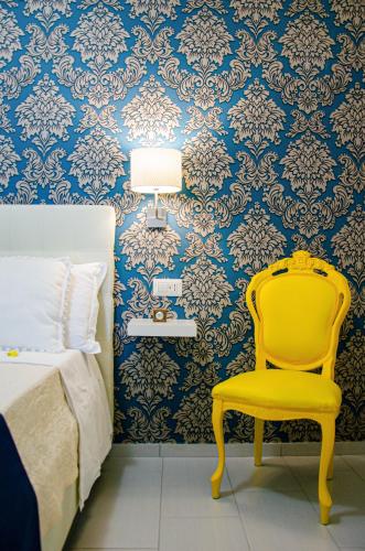 a yellow chair in a bedroom with blue and white wallpaper at La casa di pasqui in SantʼAntonio Abate