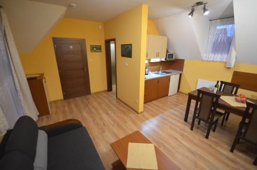 a living room with a table and a kitchen with yellow walls at Apartmány Best I. Bešeňová in Bešeňová